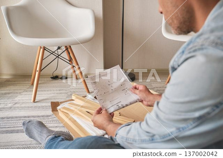 Man reading assembly instructions for new furniture 137002042