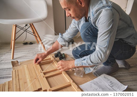 Man assembling flat pack furniture at home for renovation Man assembling flat pack furniture at home for renovation 137002051