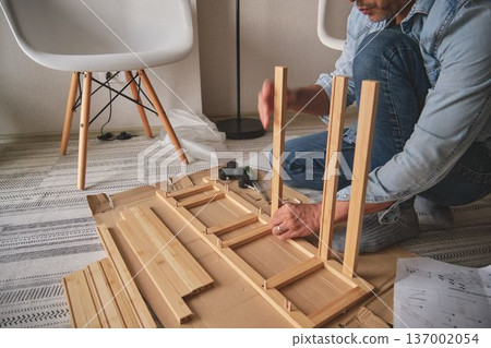 Handyman assembling wooden furniture for home improvement 137002054