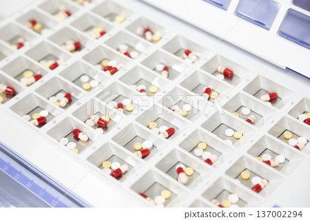 片劑和膠囊整齊地擺放在托盤上，準備包裝。 137002294