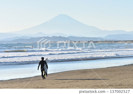 A surfer walking on the sandy beach of Kugenuma Beach with a view of Mt. Fuji A surfer walking on the sandy beach of Kugenuma Beach with a view of Mt. Fuji 137002527