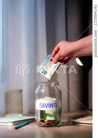 Future planning with long term savings jar. Hand adding substantial savings to future security container. Financial planning and safety concepts 137004142