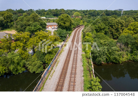 A train tracks run through a forest with a bridge over The schuykill river A train tracks run through a forest with a bridge over The schuykill river 137004548