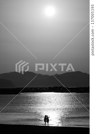 Spring arrives at Enoshima - People gazing out at the sea at Higashihama Beach in the early morning 137005193