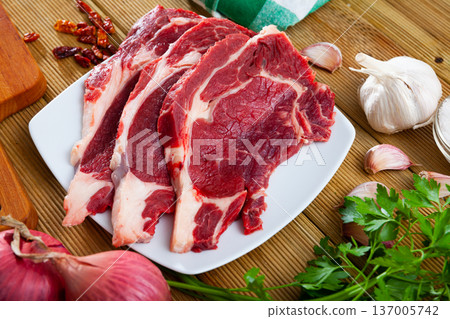 Raw veal steaks with herbs, vegetables and condiments Raw veal steaks with herbs, vegetables and condiments 137005742