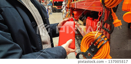 A person's hand selects one of the shovels on the store shelves. Concepts include home renovation, spring gardening preparation, construction work, DIY projects, and gardening. A person's hand selects one of the shovels on the store shelves. Concepts include home renovation, spring gardening preparation, construction work, DIY projects, and gardening. 137005817