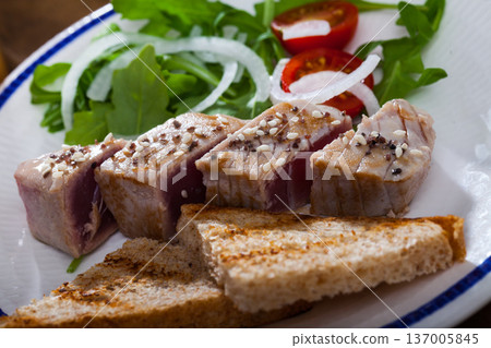 Tasty lightly fried tuna, served toasted bread and greens at plate 137005845
