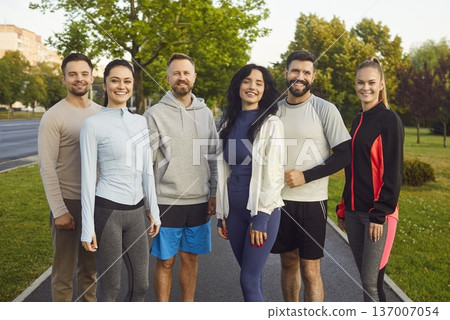 Group of happy runners standing together after jogging in summer city park Group of happy runners standing together after jogging in summer city park 137007054