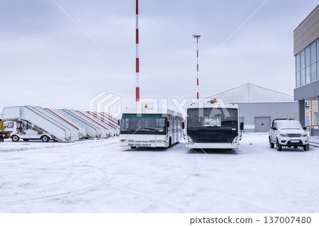 Two airport shuttle buses, empty passenger boarding steps and other equipment on the winter airport Two airport shuttle buses, empty passenger boarding steps and other equipment on the winter airport 137007480