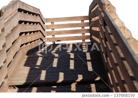 Wooden walkway structure with railing shadows creating patterns 137008150