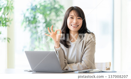 微笑的女性/女商人站在電腦前，擺出「OK」的姿勢。 137008207