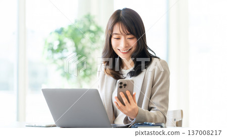 Smiling woman/businesswoman using a smartphone 137008217