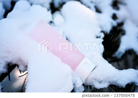 Pink cosmetics tube lying on snow covered branch 137008478