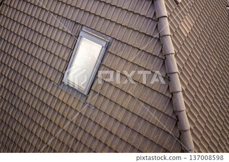 Close-up of new attic plastic window installed in shingled house roof. Professionally done building and construction work, roofing and installation concept. Close-up of new attic plastic window installed in shingled house roof. Professionally done building and construction work, roofing and installation concept. 137008598