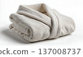Folded white bathrobe isolated on white background, soft fabric texture and clean spa aesthetic. 137008737