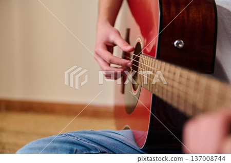 Young Person Playing Red Acoustic Guitar Close-Up Hands Strumming Guitar Strings Young Person Playing Red Acoustic Guitar Close-Up Hands Strumming Guitar Strings 137008744
