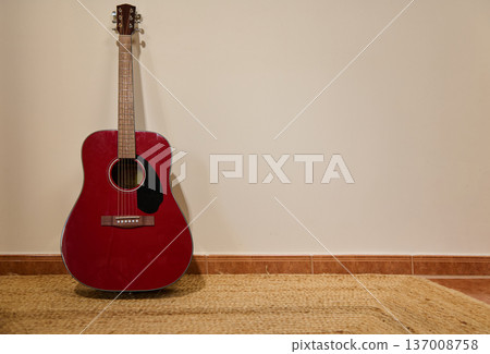 Red Acoustic Guitar Leaning Against Wall on Woven Rug in Minimal Interior Red Acoustic Guitar Leaning Against Wall on Woven Rug in Minimal Interior 137008758