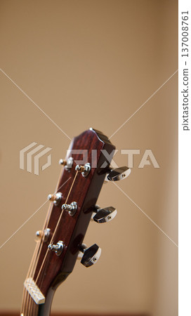 Acoustic Guitar Headstock With Tuning Pegs and Strings Close-Up On Warm Background Acoustic Guitar Headstock With Tuning Pegs and Strings Close-Up On Warm Background 137008761