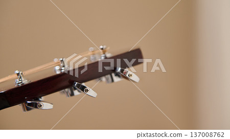 Close-Up Acoustic Guitar Headstock With Chrome Tuning Pegs On Neutral Background Close-Up Acoustic Guitar Headstock With Chrome Tuning Pegs On Neutral Background 137008762