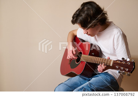 Teen Boy Playing Red Acoustic Guitar Indoors Casual Music Practice Session 137008792