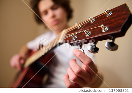 Young Person Tuning Acoustic Guitar Close-Up While Playing and Practicing Young Person Tuning Acoustic Guitar Close-Up While Playing and Practicing 137008801