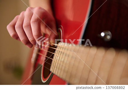 Close-Up Of Hand Playing Red Acoustic Guitar Strings In Warm Light Close-Up Of Hand Playing Red Acoustic Guitar Strings In Warm Light 137008802