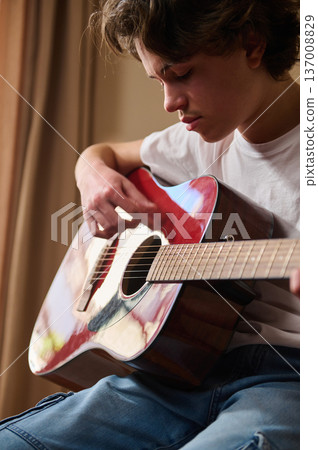 Teen Boy Playing Acoustic Guitar Indoors, Practice, Music and Concentration Teen Boy Playing Acoustic Guitar Indoors, Practice, Music and Concentration 137008829
