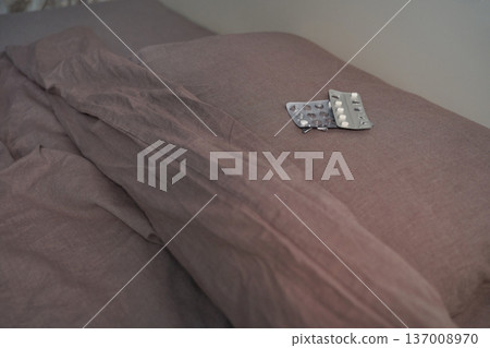 Brown bedspread with medication blister packs on pillows depicting rest and health at home Brown bedspread with medication blister packs on pillows depicting rest and health at home 137008970