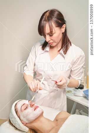 Female caucasian therapist applying facial mask to young woman at spa for skincare treatment Female caucasian therapist applying facial mask to young woman at spa for skincare treatment 137008999