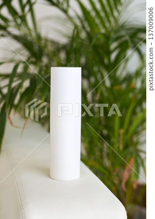 Minimalist white cylindrical container on beige surface with green plant background for skincare Minimalist white cylindrical container on beige surface with green plant background for skincare 137009006