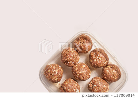 Homemade oatmeal peanut butter energy balls in square container on white background 137009014