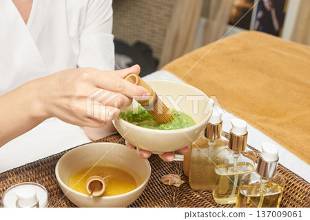 Female Prep Of Herbal Face Mask In Spa Setting With Natural Oils On Woven Mat For Relaxation Female Prep Of Herbal Face Mask In Spa Setting With Natural Oils On Woven Mat For Relaxation 137009061