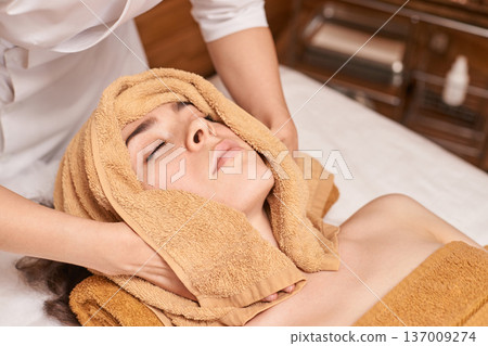 Young Caucasian Female Relaxing During Spa Facial Treatment With Towels In Tranquil Wellness Center 137009274