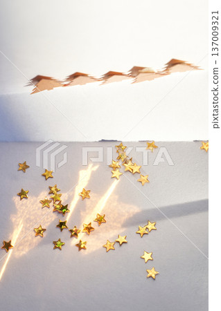Golden Star Confetti And Shadows With Cut-Out Trees On White Paper Celebrating Festive Joy Golden Star Confetti And Shadows With Cut-Out Trees On White Paper Celebrating Festive Joy 137009321