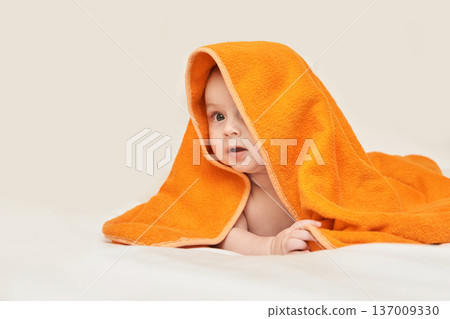 Caucasian Infant Wrapped In Orange Towel Lying On Bed Looking Curious And Playful With Happy 137009330