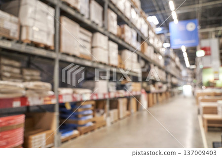 Blurred view of industrial warehouse aisle with stacked shelves and packaging materials 137009403