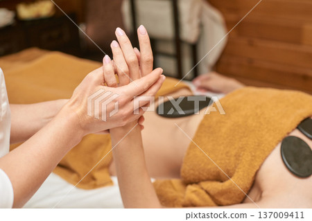 Female Receiving Professional Hand Massage And Hot Stone Therapy At Spa For Relaxation And Wellness 137009411
