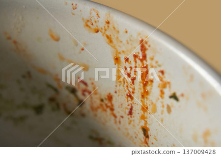Close-up view of a dirty plate with sauce stains and food residue on white surface Close-up view of a dirty plate with sauce stains and food residue on white surface 137009428