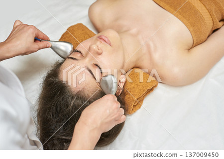 Young Female Receiving Asian Skincare Treatment With Metal Tools In Spa Setting Young Female Receiving Asian Skincare Treatment With Metal Tools In Spa Setting 137009450