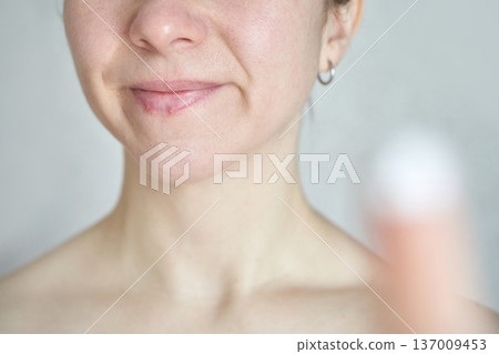 Young caucasian female with subtle smile applying skincare cream, highlighting natural beauty Young caucasian female with subtle smile applying skincare cream, highlighting natural beauty 137009453