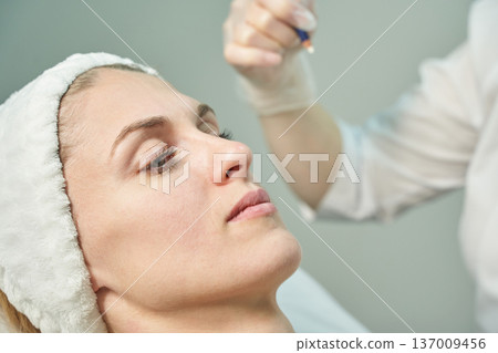 Young caucasian female receiving facial treatment in a spa setting with professional care 137009456