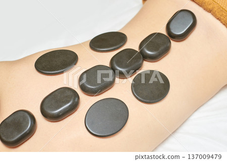 Female Enjoying Hot Stone Massage On Back For Relaxation And Stress Relief 137009479