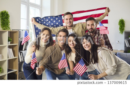 Friends celebrate US Independence Day indoors, smiling and waving American flags 137009615