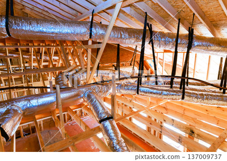 Workers install ductwork in ceiling of building that is under construction is wooden beams Workers install ductwork in ceiling of building that is under construction is wooden beams 137009737