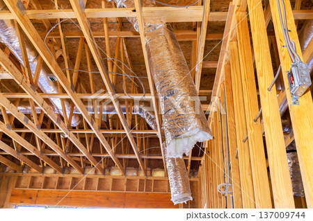 New construction site features wooden beams, HVAC ductwork, new home building progress 137009744