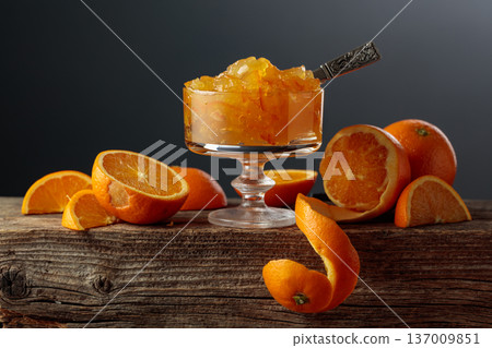 Orange jelly in a glass dessert bowl on an old wooden table. Orange jelly in a glass dessert bowl on an old wooden table. 137009851