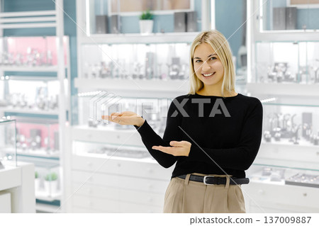 Smiling shop assistant showing jewelry in a jewelry store 137009887