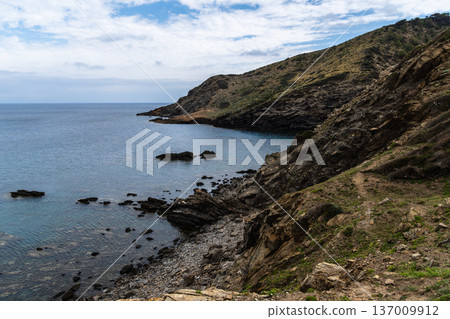 Coastal landscape of Menorca with cliffs meeting the sea under a cloudy sky. Coastal landscape of Menorca with cliffs meeting the sea under a cloudy sky. 137009912