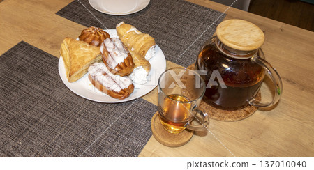 Various baked sweets on the plate and tea in a cup and teapot. Dessert 137010040