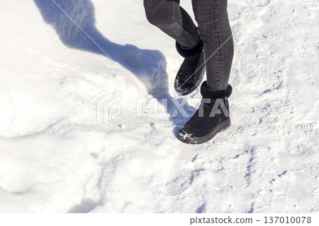 Woman wearing black ankle boots, walking on the snow. Season Woman wearing black ankle boots, walking on the snow. Season 137010078